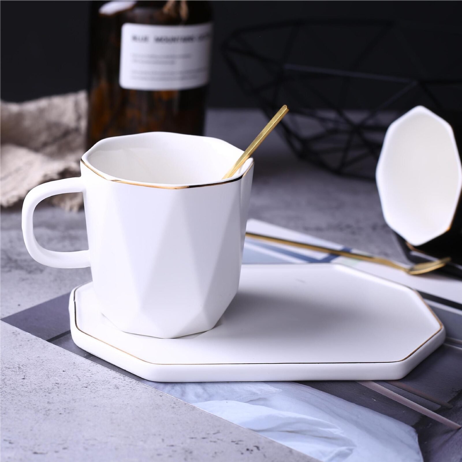 Geometric black and white ceramic cup with gold accents and saucer.