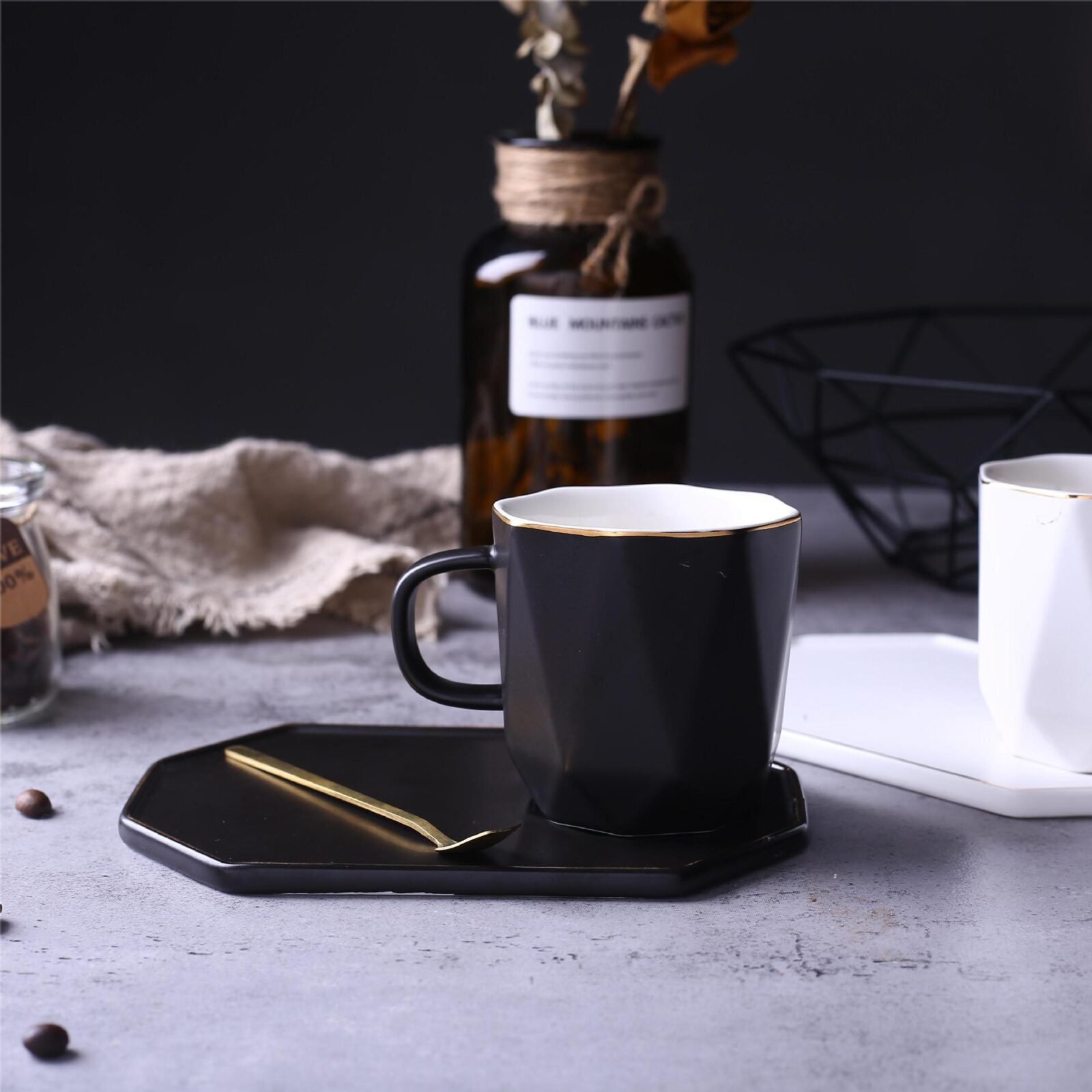 Geometric ceramic coffee mug with gold accents and saucer.